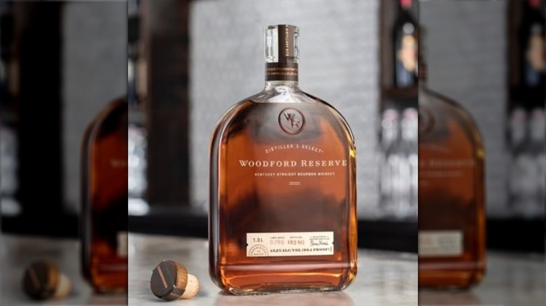 An open bottle of Woodford Reserve and its cork on a counter top