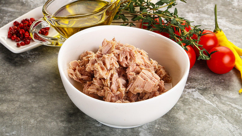 Bowl of tuna with salad ingredients around it