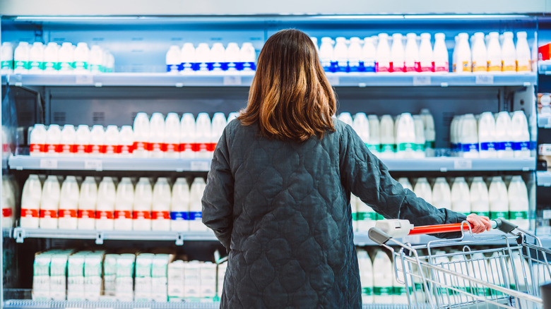A woman at the grocery store looking at shelves of dairy products