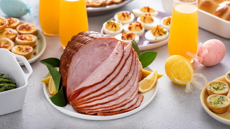 A spiral cut ham served on a table with deviled eggs and orange juice