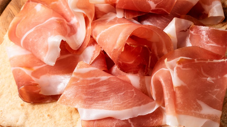 A close-up on some sliced ham on a wood board