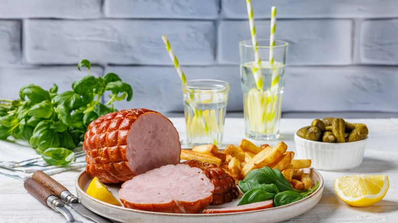 a boneless ham on plate with basil and fries and pickles