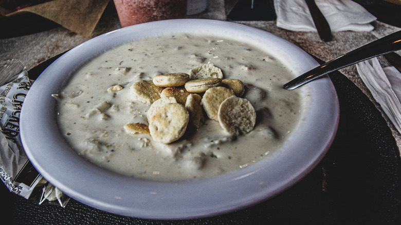 bowl of chowder topped with oyster crackers, styled on table