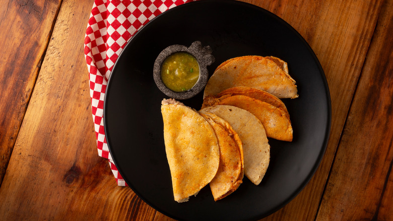 overhead shot of tacos on a black plate, wood table