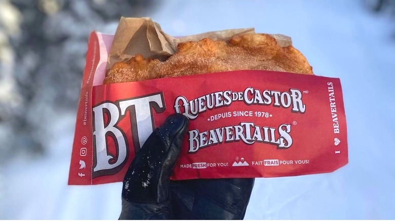 A cinnamon sugar beavertail from BeaverTails in gloved hand in snow