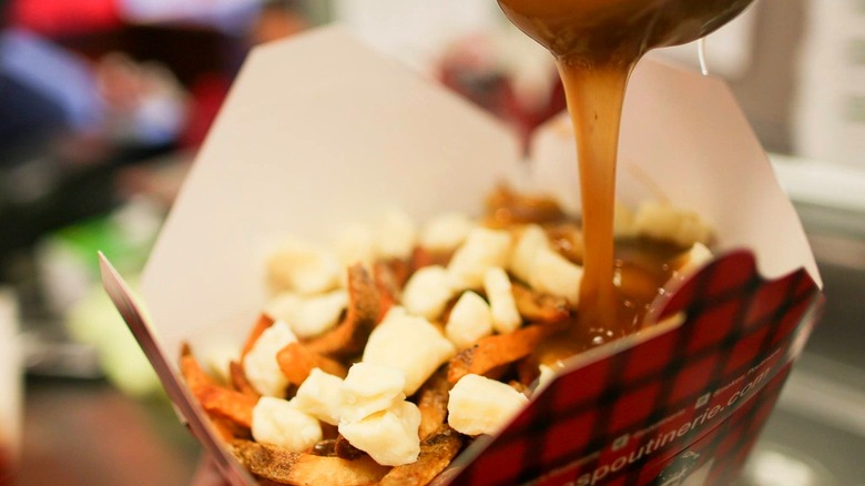 Smoke's Poutinerie poutine with gravy being poured on top
