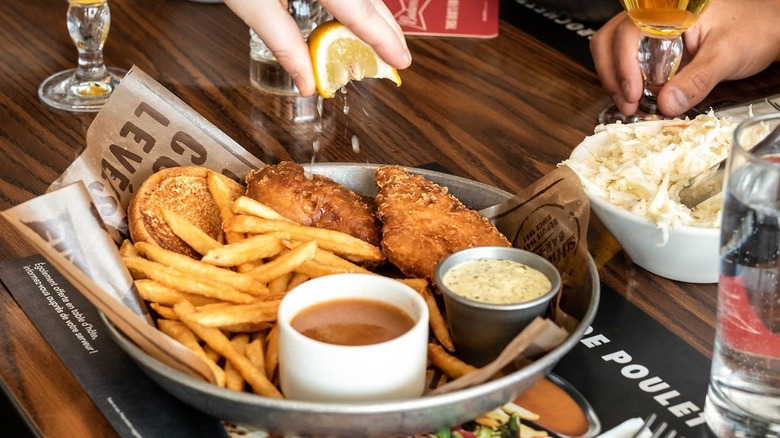 St-Hubert fish and chips on table with drinks and sides