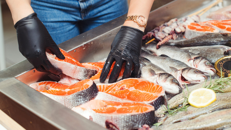 fishmonger handling fish on ice