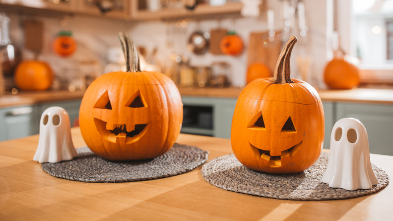 Carved pumpkins and ceramic ghosts on kitchen table