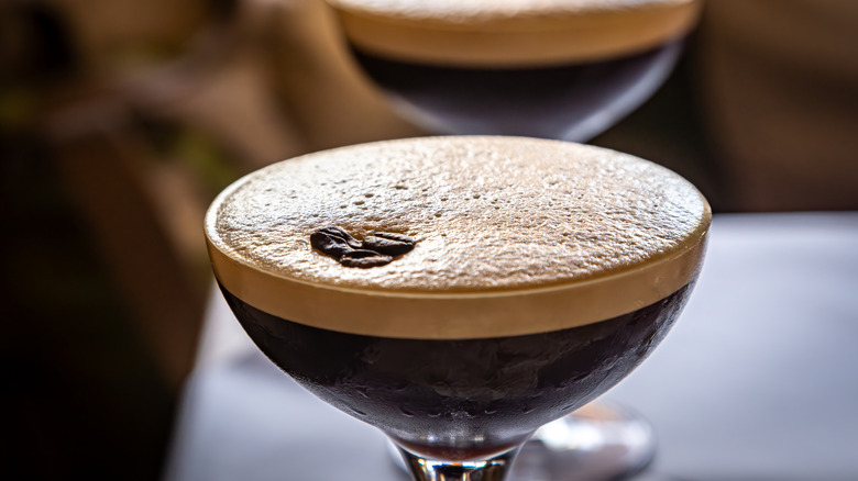 Close up of an espresso martini cocktail, with tan-colored froth and a garnish of coffee beans