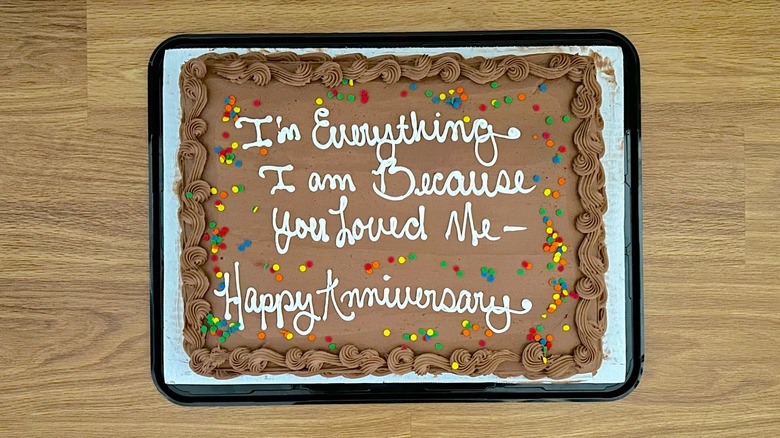 Whole custom chocolate cake from Costco decorated with colorful sprinkles and white writing