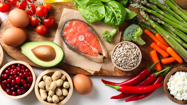 Many different foods arranged together on a wood cutting board on a white surface