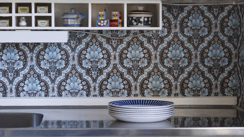 A close-up of a kitchen counter with bold blue patterned wallpaper backsplash