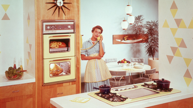 A 1950s housewife talking on the phone in her vintage kitchen
