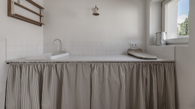 A large farmhouse sink with a striped skirt