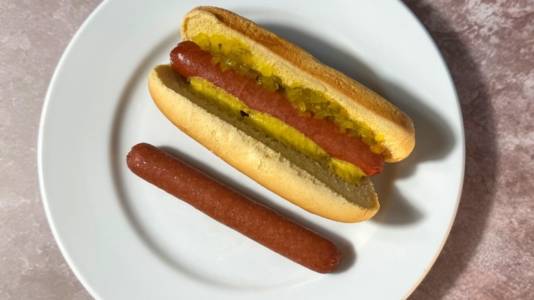 Rich brown steamed hot dogs, plain and in a bun with relish and mustard.