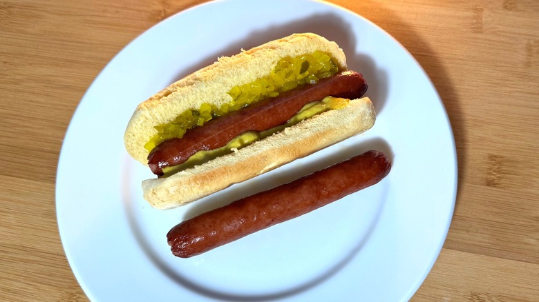 Rich brown smoked hot dogs, plain and in a bun with relish and mustard.