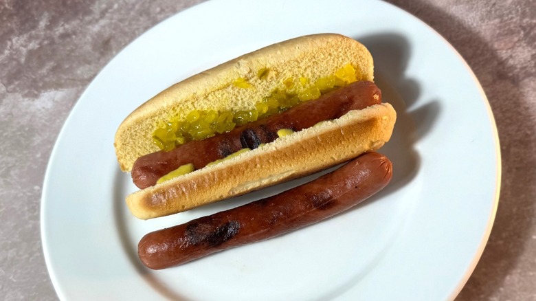 Lightly charred flame-grilled hot dogs, plain and in a bun with relish and mustard.