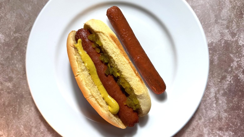 Rich brown beer-simmered hot dogs, plain and in a bun with relish and mustard.