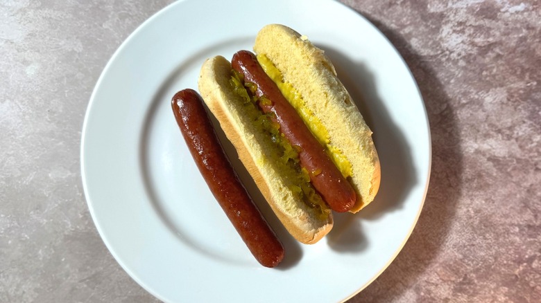 Rich brown oven-roasted hot dogs, plain and in a bun with relish and mustard.