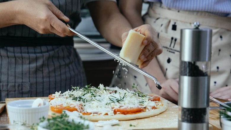 grating cheese over pizza