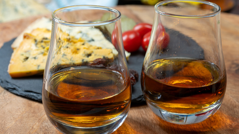 Two whiskey tasting pours in front of a cheese and vegetable board of palate cleansers