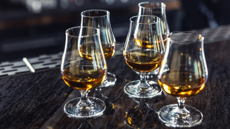 A group of five whiskey glasses on a bar top