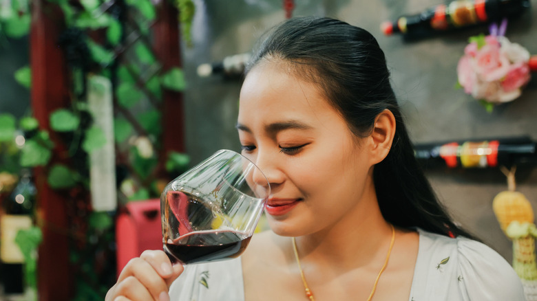 A young woman sniffing a glass of red wine