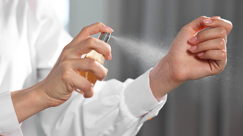 A closeup of a person spraying their wrist with perfume or cologne