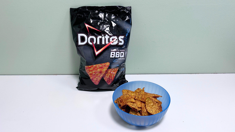A bowl of chips next to a bag of Doritos Sweet and tangy BBQ Chips