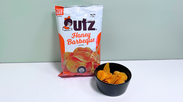 A bowl of chips next to a bag of Utz Honey Barbeque Chips