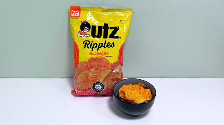 A bowl of chips next to a bag of Utz Ripples Barbeque Chips