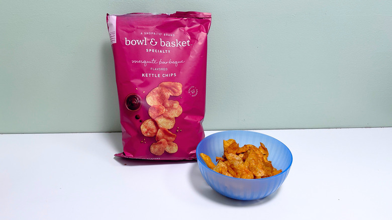 A bowl of chips next to a bag of Bowl and Basket Barbeque Kettle Chips