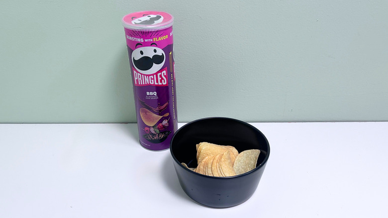 A bowl of chips next to a can of Pringles BBQ Chips