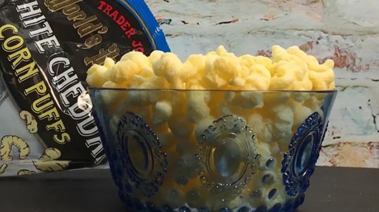 A bowl of Trader Joe's World's Puffiest White Cheddar Corn Puffs with the bag visible in the background