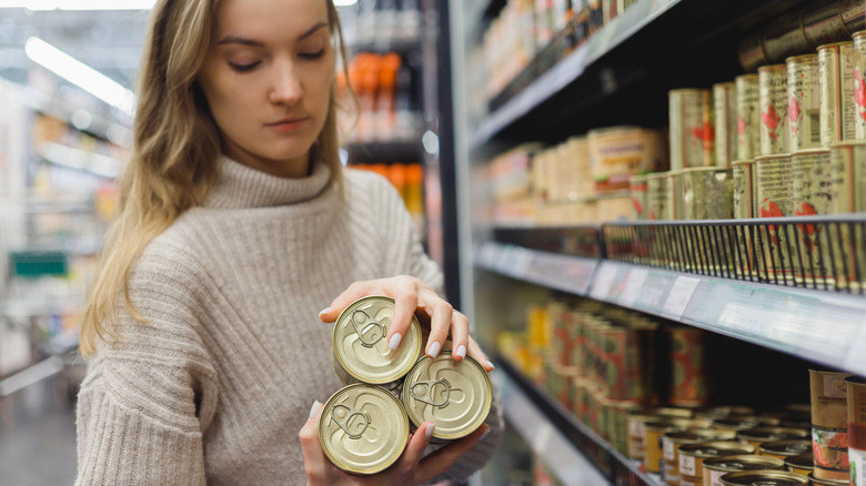 A woman holding three canned goods