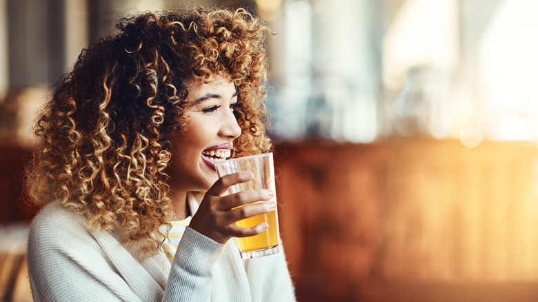 A woman drinking a beer and smiling