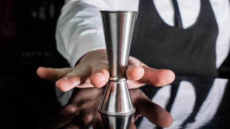 hand grabbing cocktail jigger