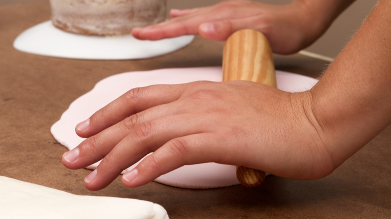 person rolling out fondant