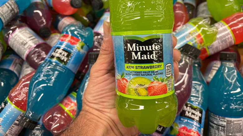 Person holding a bottle of Minute Maid kiwi strawberry with bottles in the background