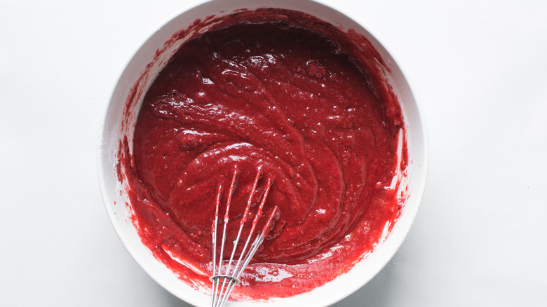 Red velvet cake batter in a bowl with a whisk