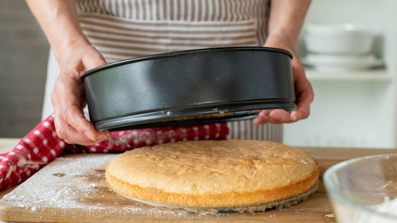 A woman removing a cake from a dark cake pan