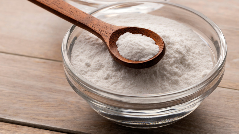 Baking powder in a bowl with a wooden spoon