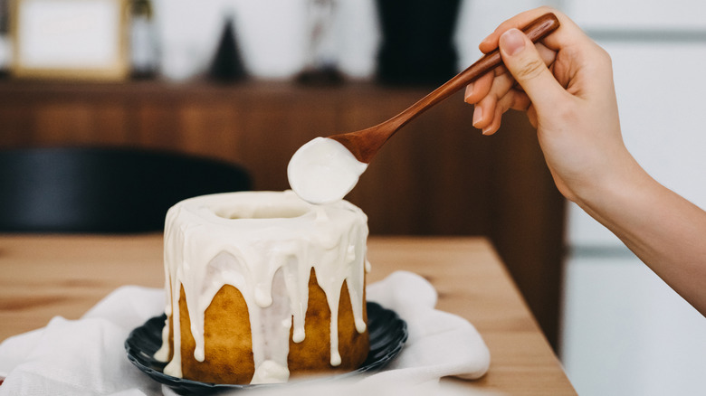 Person frosting a cake with a wooden spoon