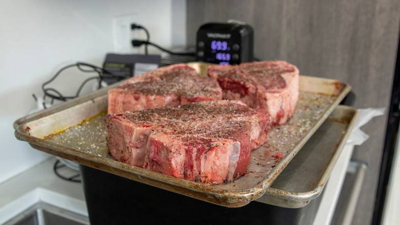 Raw T-bone steaks on a baking sheet