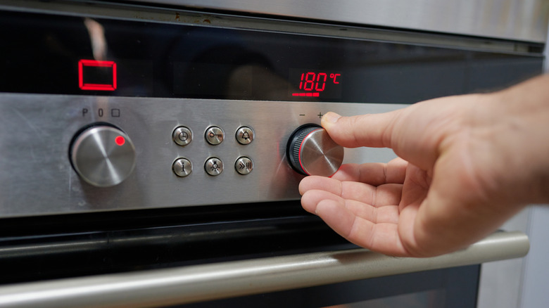 Hand adjusting temperature on an oven