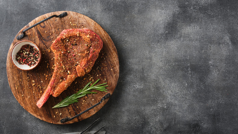Tomahawk steak with a dry rub on wooden cutting board