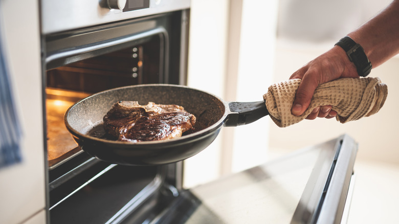 Person cooking a T-bone steak in the oven