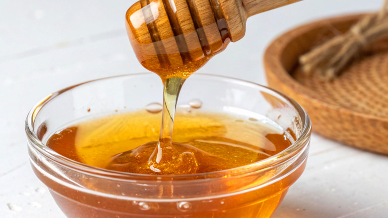 Honey drizzles from a dipper into a bowl