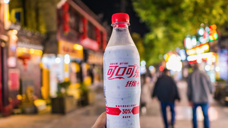 A white and red bottle of Coca-Cola Fiber Plus against a background of a Chinese city at night.